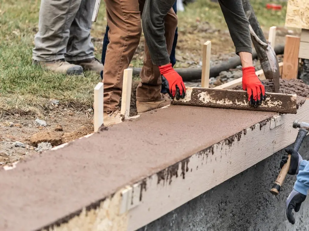 A worker repairing a cracked section of a concrete pool surround