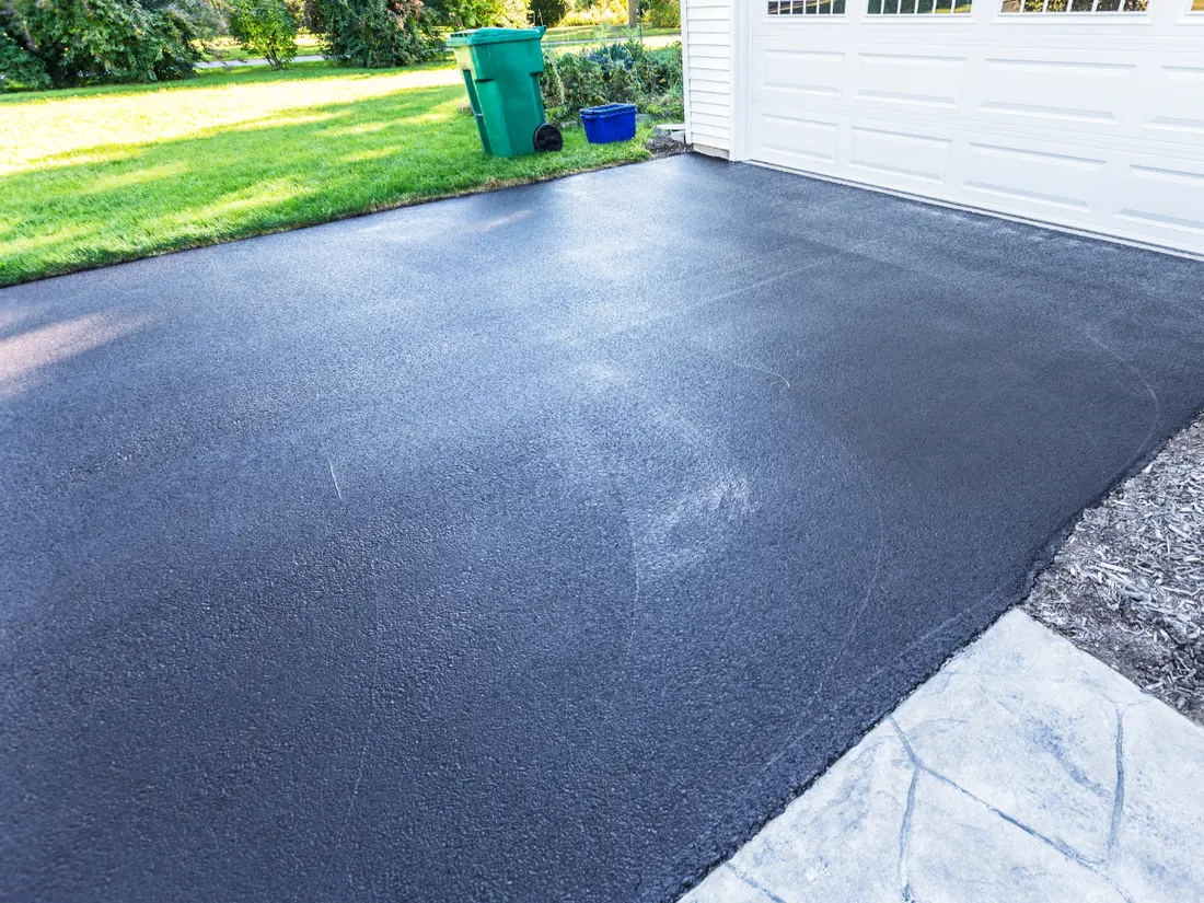 Side by side comparison of a concrete driveway and an asphalt surface