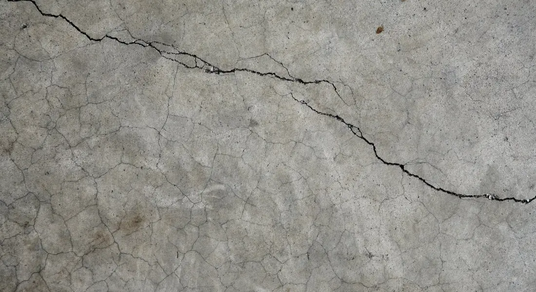 A concrete industrial floor with a crack being assessed for repair