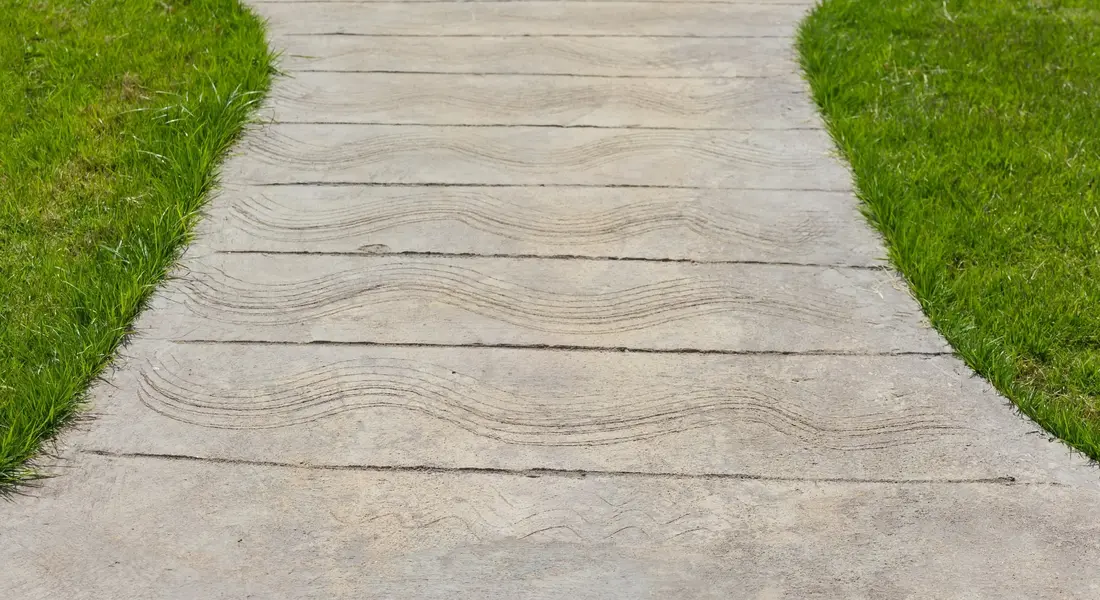 A neatly designed concrete walkway through a garden