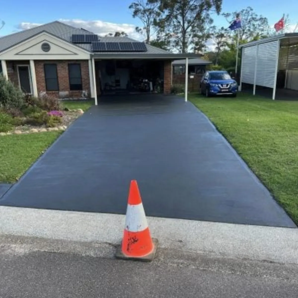 A freshly sealed charcoal concrete driveway