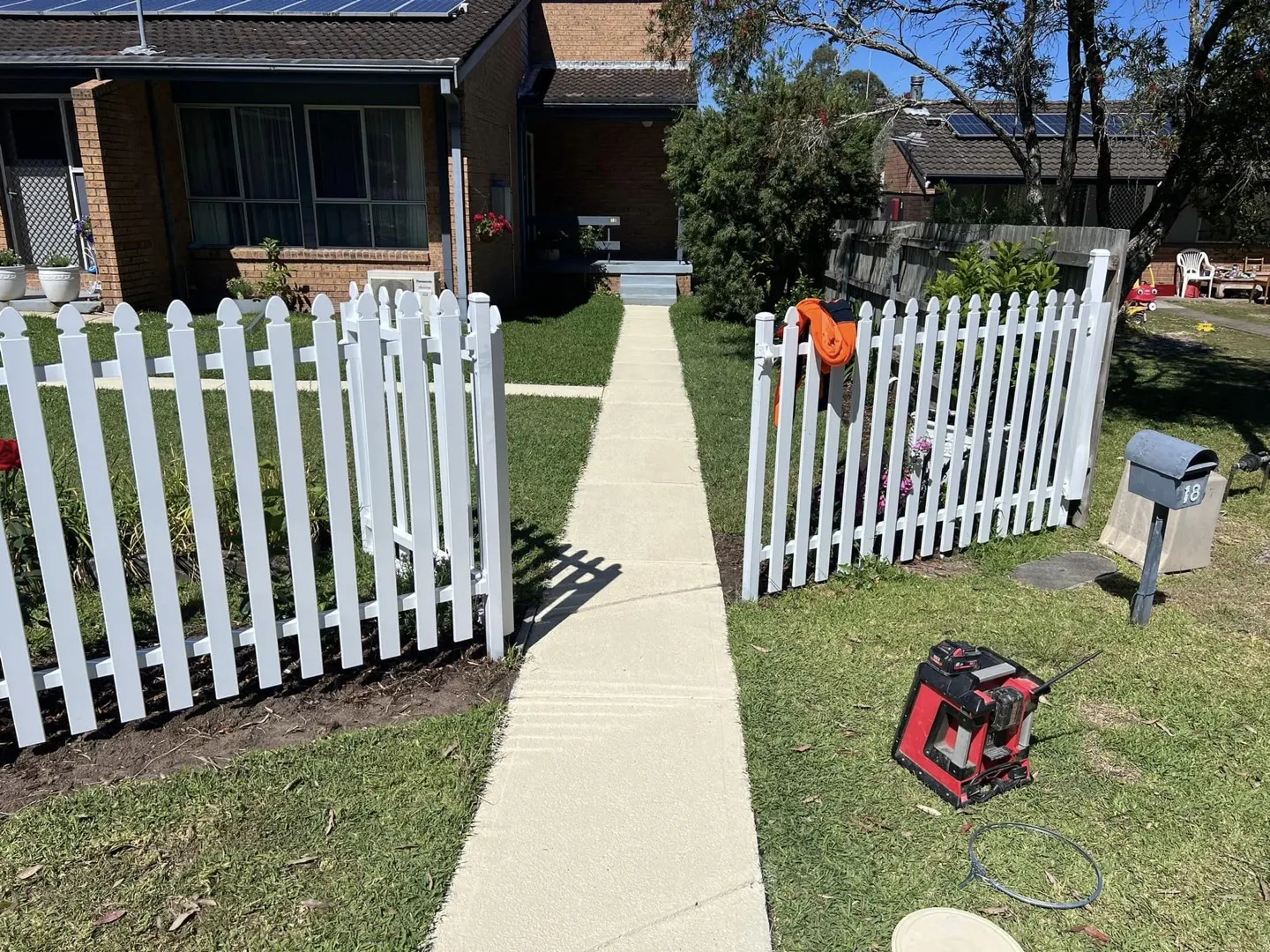 A fresh concrete pathway beside a white picket fence