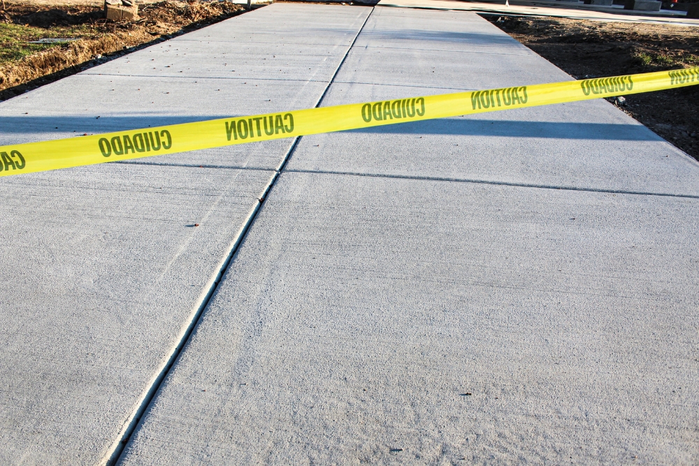 A newly poured grey concrete driveway or sidewalk with control joints.