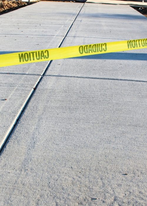 A newly poured grey concrete driveway or sidewalk with control joints.